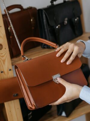 A stylish leather handbag being presented in a sleek, modern showroom setting.