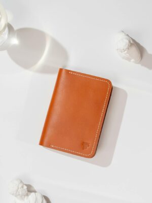 Stylish brown leather wallet on white surface with artistic lighting.