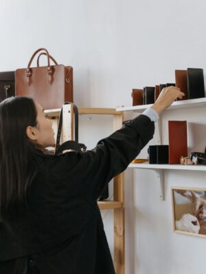Woman browsing leather bags and wallets in a stylish retail shop.