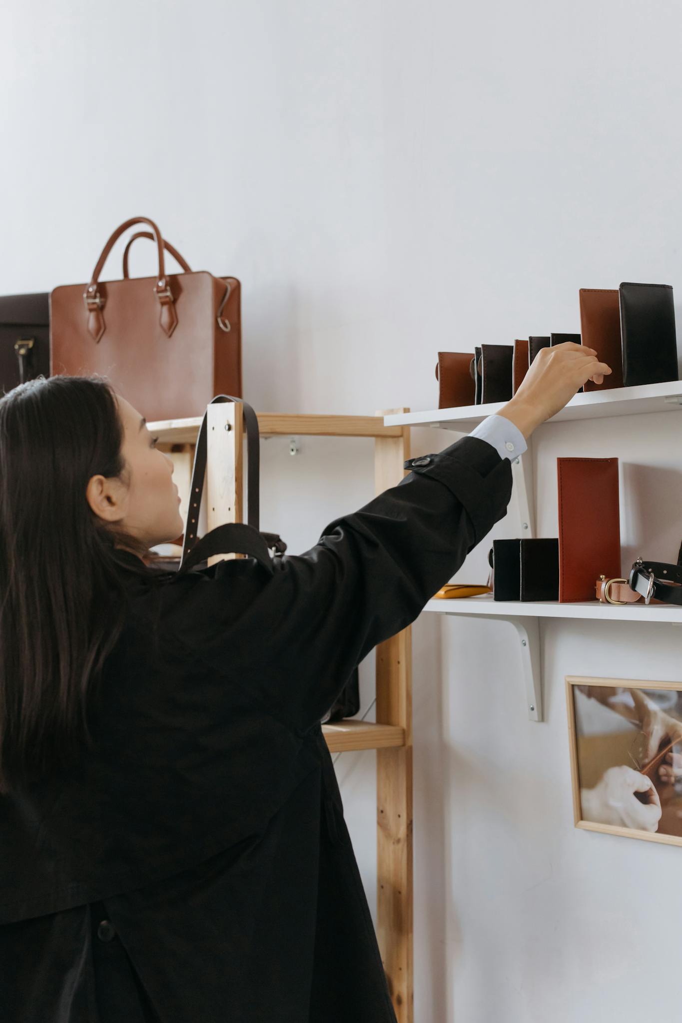 Woman browsing leather bags and wallets in a stylish retail shop.